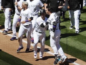 Colorado Rockies' Nolan Arenado, front right, is restrained by Carlos Gonzalez, centre, as Gerrardo Parra, left, keeps an eye on the San Diego Padres dugout after Arenado rushed the mound Wednesday, April 11, 2018, in Denver.