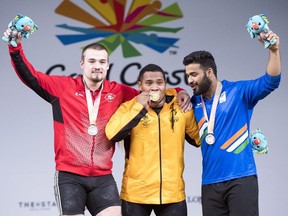 Silver medalist Boady Santavy, from Canada, gold medal winner Steven Kari, Papua New Guinea, and bronze medalist Vikas Thakur, from India, wave from the podium after the men's 94kg weightlifting finals at the Commonwealth Games Sunday, April 8, 2018 in Gold Coast, Australia.