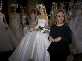 Fashion designer Reem Acra, center, join models after showing her latest bridal collection, during Bridal Fashion Week, Thursday April 12, 2018 in New York.