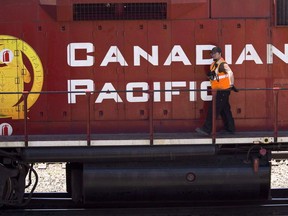 A Canadian Pacific Railway employee walks along the side of a locomotive in a marshalling yard in Calgary, Wednesday, May 16, 2012.