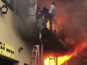 In this Monday, April 9, 2018 photo, girls flee a second-story dance studio onto a balcony as a roaring fire engulfs their building in Edgewater, N.J.