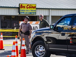 Police look up as a helicopter flies overhead outside of Ace China after a shooting in Trenton, Fla., Thursday, April 19, 2018. Someone fired through the window of a north Florida restaurant Thursday afternoon, killing two deputies who were getting food, officials said.