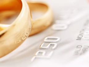 In this stock photo, wedding rings lay on top of a credit card.