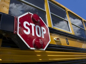 In this stock photo, a yellow school bus with a stop sign is seen with clouds reflecting in the windows.