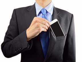In this stock photo, a businessman puts his cellphone in his pocket jacket.