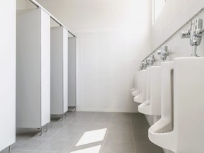 In this stock photo, urinals and stalls are seen in a men's public washroom.