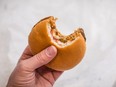 In this stock photo, a man holds a fast food burger with a bite out of it.