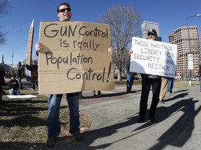 This Jan. 9, 2013 file photo shows Craig Larson, right, of Fort Collins, Colo., and another protester who refused to identify himself waving signs during a pro-gun rally in a park across from the State Capitol in Denver. (AP Photo/David Zalubowski, File)