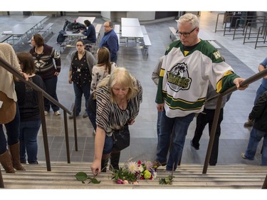 Humboldt mayor Rob Muench, in the Broncos jersey, along with other mourners lay down flower on the stairs that enter to Elgar Petersen Arena, home of the Humboldt Broncos, in Humboldt, Sask., on Saturday, April 7, 2018. RCMP say 14 people are dead and 14 people were injured Friday after a truck collided with a bus carrying a junior hockey team to a playoff game in northeastern Saskatchewan. Police say there were 28 people including the driver on board the Humboldt Broncos bus when the crash occurred at around 5 p.m. on Highway 35 north of Tisdale.