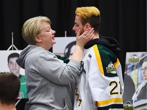 Humboldt Broncos' Nick Shumlanski, who was released from hospital earlier today, is comforted by a mourner during a vigil at the Elgar Petersen Arena, home of the Humboldt Broncos, to honour the victims of a fatal bus accident, April 8, 2018 in Humboldt, Sask. (JONATHAN HAYWARD/AFP/Getty Images)