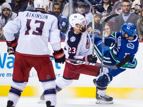 Columbus Blue Jackets' Ian Cole (23) checks Vancouver Canucks' Brandon Sutter, right, during the second period of an NHL hockey game in Vancouver on March 31, 2018. (THE CANADIAN PRESS/Darryl Dyck)