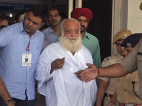 FILE- In this Sept. 1, 2013 file photo, controversial spiritual guru Asaram Bapu, center, is brought for interrogation by police at Jodhpur airport in Jodhpur, India.