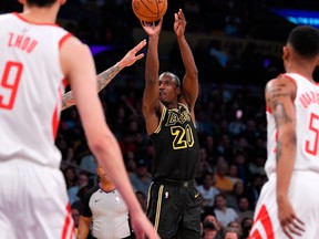 Los Angeles Lakers guard Andre Ingram, center, shoots as Houston Rockets forward Zhou Qi, left, of China, and guard Tim Quarterman watch during the second half of an NBA basketball game on April 10, 2018