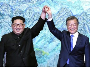 North Korean leader Kim Jong Un, left, and South Korean President Moon Jae-in raise their hands after signing a joint statement at the border village of Panmunjom in the Demilitarized Zone, South Korea, Friday, April 27, 2018.