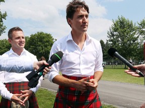 Prime Minister Justin Trudeau, wearing kilt, talks to reporters as M.P. Francis Drouin looks on while attending the 70th annual Glengarry Highland Games in Maxville, Ont., Friday, August 4, 2017.