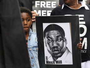 Rapper Meek Mill's son Papi holds a sign as protesters demonstrate in front of a courthouse during a hearing for Meek Mill, Monday April 16, 2018 in Philadelphia. The city's district attorney says Mill's convictions should be vacated and he should have a new trial. The announcement came during a hearing on Monday, but a judge is still refusing to release Mill on bail. Philadelphia-born Mill was sentenced in November 2017 to two to four years in prison for violating probation on a roughly decade-old gun and drug case.