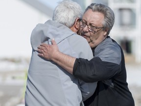 Myles Shumlanski, right, receives a hug at a makeshift memorial at the intersection of of a fatal bus crash near Tisdale, Sask., Tuesday, April, 10, 2018. (THE CANADIAN PRESS/Jonathan Hayward)