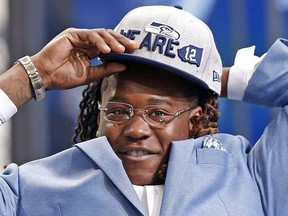 Shaquem Griffin puts on a Seattle Seahawks cap during the NFL football draft in Arlington, Texas, Saturday, April 28, 2018. (Jae S. Lee/The Dallas Morning News via AP) ORG XMIT: TXDAM901