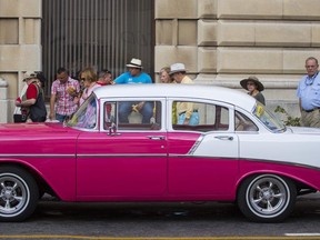 FILE - In this Feb. 22, 2016, file photo, tourists look at a classic American car parked beside the cruise ship terminal in Havana, Cuba. Cuba is one of four destinations where a new trip-planning company called ViaHero is offering its services. For a flat fee of $25 a day, a ViaHero expert on the ground in your destination plans your trip, from lodging and airport pick-up to what to see and where to eat. The service combines authentic local recommendations, the convenience of online booking and the old-school guidance of a travel agent. In addition to Cuba, ViaHero plans trips in Iceland, Japan and Colombia.