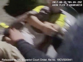 In this Aug. 25, 2017 image made from video and released by the Asheville, (N.C.) Police Department, Johnnie Jermaine Rush grimaces after officer Christopher Hickman overpowers Rush in a chokehold, in Asheville, N.C.