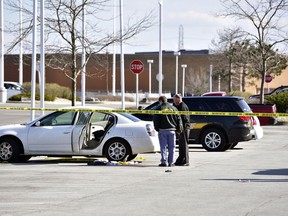 In this Tuesday, April 17, 2018 photo, police work the scene where  a 3-year-old girl accidentally shot and wounded her pregnant mother in a car parked outside a northwestern Indiana thrift store. The shooting happened Tuesday afternoon in Merrillville, Ind., as the girl, a 1-year-old boy and her mother waited in the car while the woman's boyfriend was inside the store. Police say the man is the girl's father and apparently left the loaded gun in the car.