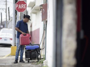 Juan Castro fills a generator with gasoline to energize the cabinet-building workshop where he works, in San Juan, Puerto Rico, Wednesday, April 18, 2018. (Carlos Giusti/AP Photo)