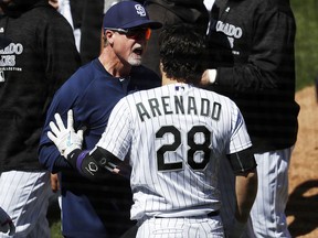 San Diego Padres bench coach Mark McGwire, left, restrains Colorado Rockies' Nolan Arenado after he charged the mound Wednesday, April 11, 2018, in Denver. (AP Photo/David Zalubowski)