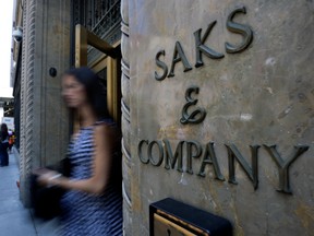 In this July 29, 2013, file photo, a shopper uses a Fifth Avenue entrance to Saks, in New York. (AP Photo/Richard Drew, File)