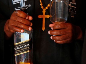 A bottle of whiskey is prepared to anoint a priest with whiskey into the Gabola Church during a service in a bar in Orange Farm, south of Johannesburg Sunday, April 15, 2018.