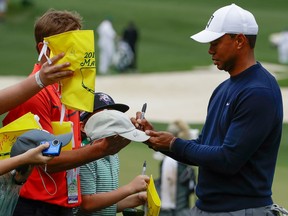Tiger Woods signs some autographs on the range before a practice round for the Masters on April 4, 2018