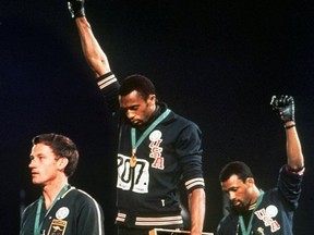 In this Oct. 16, 1968, file photo, Australian silver medalist Peter Norman, left, stands on the podium as Americans Tommie Smith, centre, and John Carlos raise their gloved fists in a human rights protest. Australian Olympic Committee (AOC) awarded on Saturday, April 28, 2018, a posthumous Order of Merit to Norman. AOC President John Coates said that Norman's achievements as an athlete - his silver-medal winning time of 20.06 seconds at Mexico City remains an Australian record 50 years after he set the mark - were dwarfed by his support for the gold and bronze medalists who raised their gloved fists and bowed their heads during the American national anthem. (AP Photo, File)
