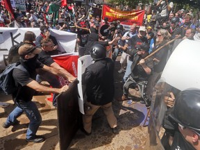In this Saturday, Aug. 12, 2017, photo, white nationalist demonstrators clash with counter demonstrators at the entrance to Lee Park in Charlottesville, Va. (AP Photo/Steve Helber)