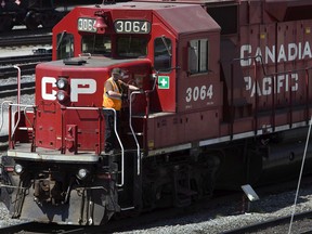 A Canadian Pacific Railway employee walks along the side of a locomotive in a marshalling yard in Calgary, Wednesday, May 16, 2012. THE CANADIAN PRESS/Jeff McIntosh