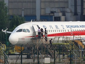 This photo taken on May 14, 2018 shows employees checking a Sichuan Airlines Airbus A319 after an emergency landing, as a broken cockpit window (L) is covered, in Chengdu in China's northwestern Sichuan province. (Getty Images)