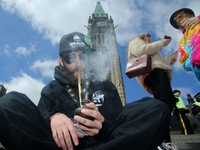 A man smokes marijuana from a bong during the annual 4/20 marijuana celebration on Parliament Hill in Ottawa on Friday, April 20, 2018.