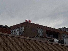 An individual brandishes a Nazi flag on a rooftop during a May Day protest in Montreal.