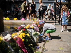 A young boy places a decorated stone among the floral tributes, on the first anniversary of the terrorist attack in central Manchester, on May 22, 2018 in Manchester, England.  The suicide bomb attack took place following a concert at Manchester Arena by US singer Ariana Grande and claimed the lives of 22 people.