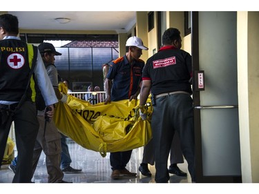 Indonesian police and medical personnel bring the body of a victim to a hospital in Surabaya on May 13, 2018.