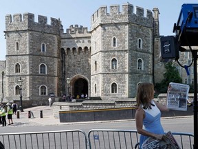 A CNN reporter holds up a copy of the British Sun newspaper leading with a story of Meghan Markle's father, Thomas Markle, opposite the Henry VII Gate of Windsor Castle in Windsor on May 15, 2018. (ADRIAN DENNIS/AFP/Getty Images)