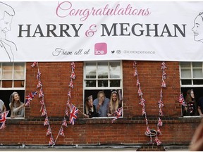 Royal fans lean out of windows as they watch Britain's Prince Harry and his best man Prince William, Duke of Cambridge, greet well-wishers on the street outside Windor Castle in Windsor on May 18, 2018, the eve of Prince Harry's royal wedding to US actress Meghan Markle. Britain's Prince Harry and US actress Meghan Markle will marry on May 19 at St George's Chapel in Windsor Castle.