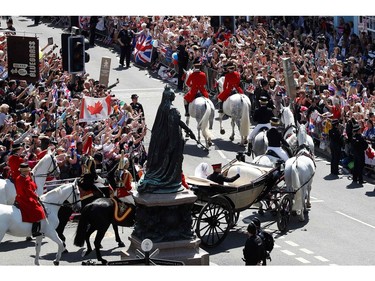 Well-wishers lining the streets wave and cheer as Britain's Prince Harry, Duke of Sussex and his wife Meghan, Duchess of Sussex pass riding in the Ascot Landau Carriage during their carriage procession taking the turn from Castle Hill onto the High Street outside Windsor Castle in Windsor, on May 19, 2018 after their wedding ceremony.