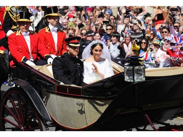 Britain's Prince Harry, Duke of Sussex and his wife Meghan, Duchess of Sussex wave from the Ascot Landau Carriage during their carriage procession on the High Street in Windsor, on May 19, 2018 after their wedding ceremony.