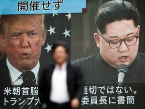 A pedestrian walks in front of a screen in Tokyo on May 25, 2018 flashing a news report relating to US President Donald Trump and North Korean leader Kim Jong Un.