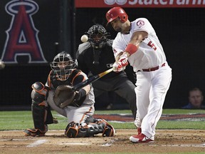 In this May 2, 2018, file photo, Los Angeles Angels star Albert Pujols, right, hits a home run in front of Baltimore Orioles catcher Caleb Joseph, left, and home plate umpire Roberto Ortiz in Anaheim, Calif.