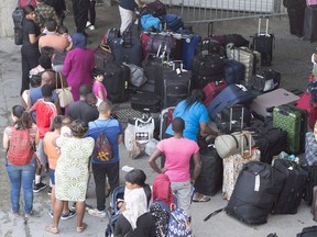 Asylum seekers line up to enter Olympic Stadium Friday, August 4, 2017 near Montreal, Quebec.