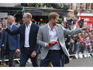 Britain's Prince Harry walks back carrying a cuddly toy after he greeted crowds with his brother Prince William in Windsor, near London, England, Friday, May 18, 2018. Preparations continue in Windsor ahead of the royal wedding of Britain's Prince Harry and Meghan Markle on Saturday May 19.