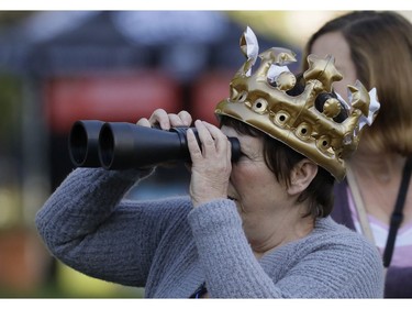A woman with an inflatable crown looks through binoculars prior to the wedding ceremony of Prince Harry and Meghan Markle at St. George's Chapel in Windsor Castle in Windsor, near London, England, Saturday, May 19, 2018.