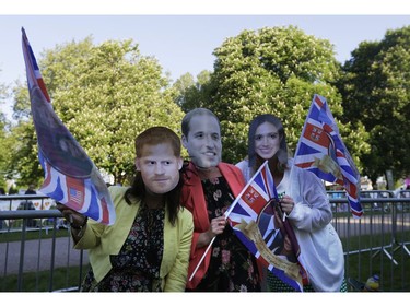 Women wear masks of Britain's Prince Harry, Britain's Prince William and Meghan Markle, from left, prior to the wedding ceremony of Prince Harry and Meghan Markle at St. George's Chapel in Windsor Castle in Windsor, near London, England, Saturday, May 19, 2018.