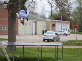 A child does a back flip on the trampoline with the fire hall seen in the background, in Nickerson, Neb., Tuesday, April 19, 2016.