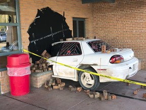 This photo taken Wednesday, May 16, 2018, and provided by Ritchie Narges, shows what looks to be a car that crashed into the principal's office at Cumberland High School in Cumberland, Wis., but is actually an illusion created for a senior class prank. (Ritchie Narges via AP)